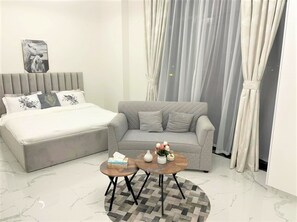 Relax in a spacious room with a large bed, sofa, and small table, perfect for unwinding.