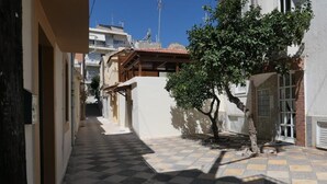 Une ruelle étroite, avec un sol pavé de carreaux, un arbre et des bâtiments de chaque côté.