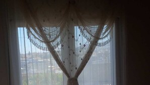 Une pièce dotée d’une grande fenêtre ornée de rideaux légers et présentant un motif floral.
