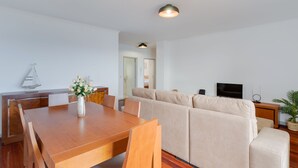 A modern living room with a wooden dining table, beige sofa, and a television. - Santa Cruz Apartment (Santa Cruz)