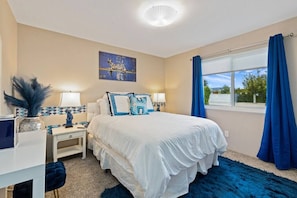A bedroom with a bed, bedside tables, lamps, a decorative vase, and a window with curtains.