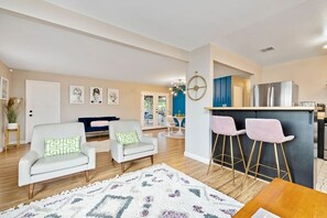 Een moderne woonkamer met een bank, stoelen, een vloerkleed en een bar met barkrukken.