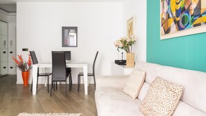 A modern living room with a white sofa, a dining area with a white table and black chairs, and a teal accent wall. - Groovy Apartment: nice, modern and quiet house in the heart of Milan - 4 guests  (Milano)