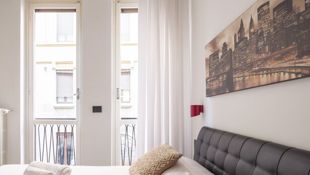 A hotel room with a bed, a cityscape painting, and a view through a window. - Groovy Apartment: nice, modern and quiet house in the heart of Milan - 4 guests  (Milano)