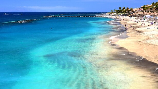 A beach with clear turquoise waters, a sandy shore, and a rocky breakwater. - Elegant Villa with private pool and ocean view (CN)