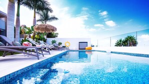 A swimming pool with lounge chairs and umbrellas, surrounded by palm trees and a clear sky. - Elegant Villa with private pool and ocean view (CN)