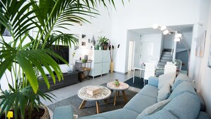 A modern living room with a sofa, two round coffee tables, and a large potted plant. - Elegant Villa with private pool and ocean view (CN)