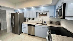 A modern kitchen with stainless steel appliances, light blue cabinets, and a tiled floor.