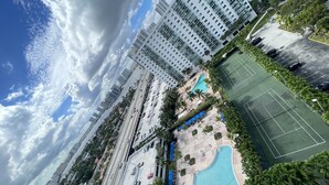 A high-rise building with multiple floors, a swimming pool, and a tennis court.