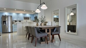 A modern kitchen with a central island, stainless steel appliances, and a dining area with a table and chairs.
