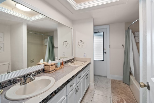 A bathroom with two sinks, a large mirror, and a shower. - Waterfront 3BR Marco Island home with heated pool and WiFi. (Marco Island)