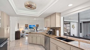 A modern kitchen with a large island, built-in appliances, and a view to the outside.