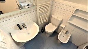 Ein kleines Badezimmer mit Waschbecken, Toilette, Bidet und Spiegel.
