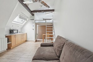 Ein kompakter Wohnbereich mit Schlafgalerie, Küchenzeile und einer Couch.