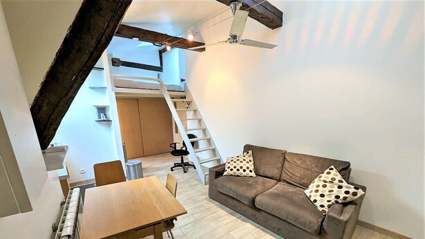 Ein kompakter Wohnraum mit Schlafgalerie, Essbereich und einer Couch mit Punkte-Kissen.