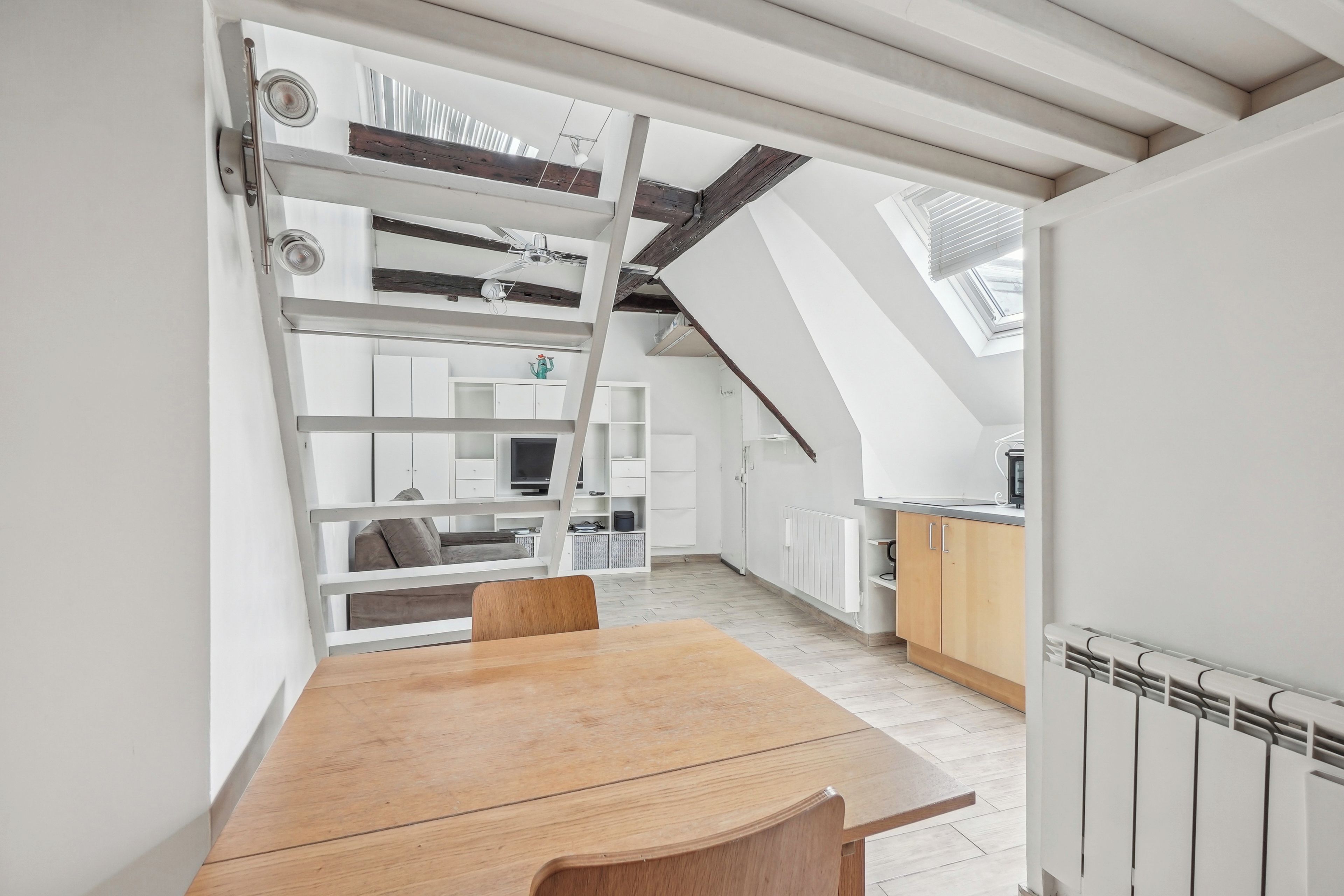 A modern interior with a dining area, kitchen, and loft space.