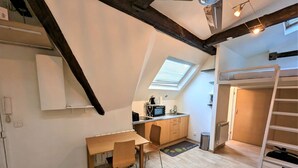 Ein kompakter Wohnraum mit Küche, Essbereich und einer Schlafgalerie mit Etagenbett.
