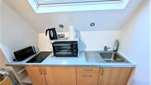 Eine kompakte Küche mit Einbauofen, Toaster, Spüle und einem Fenster über der Arbeitsfläche.