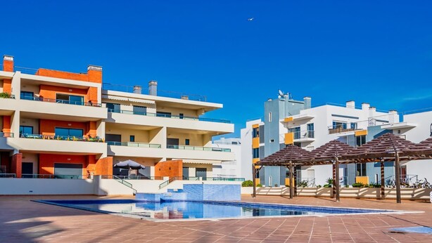 A modern residential complex with a swimming pool and outdoor seating areas.