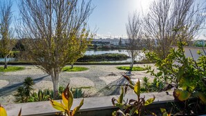 A park with trees, a gravel path, and a body of water in the background.