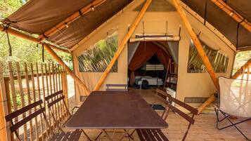 A tent with a table and benches, a bunk bed, and a ladder.