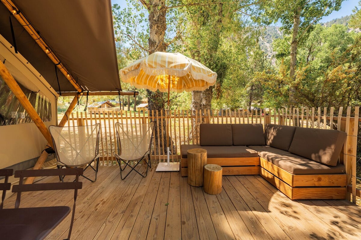 A wooden deck with a sofa, chairs, and a hanging umbrella.