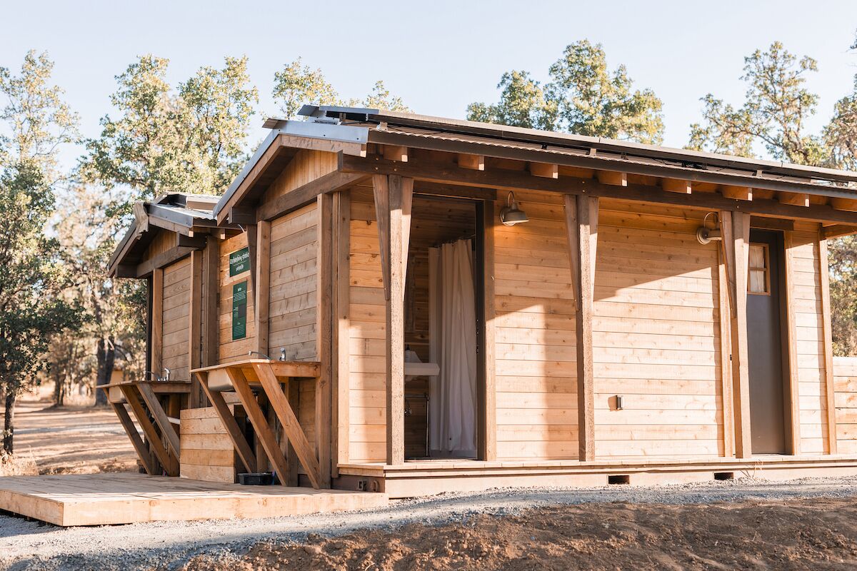 A wooden cabin with a covered porch, a small outdoor seating area, and a door leading to the interior.