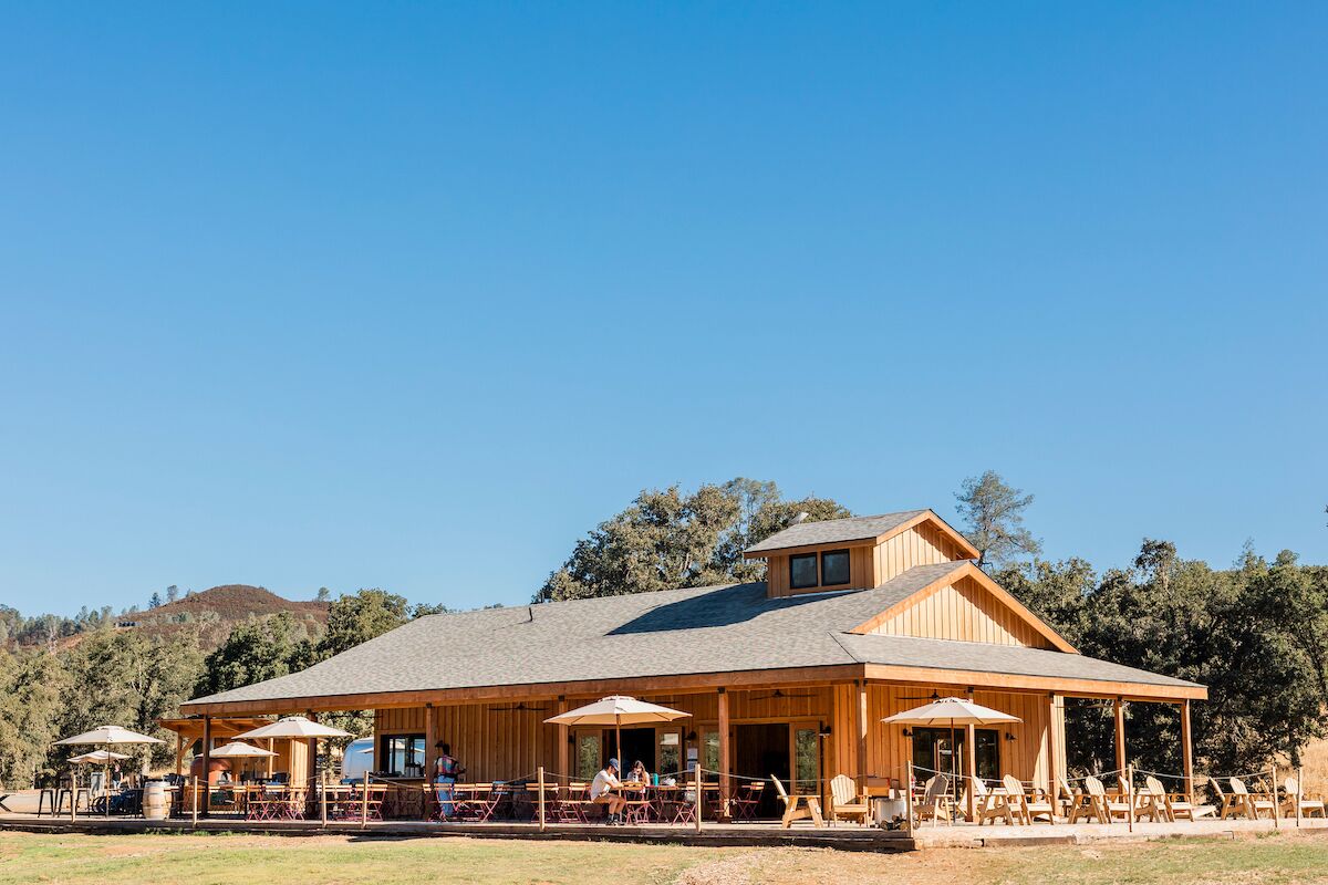 A wooden building with outdoor seating and a covered patio area.