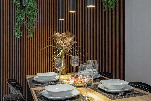 Mesa de jantar posta com pratos, copos e um arranjo central.