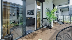 Un balcon moderne avec une porte vitrée donnant sur un espace de vie intérieur, une plante en pot et une chaise.