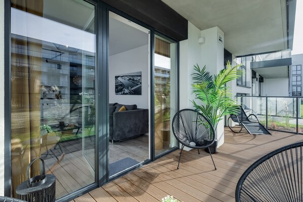 A modern balcony with a glass door leading to an interior living area, a potted plant, and a chair. - Elegant Suite with Spa Area | Jacuzzi (Dziwnów)