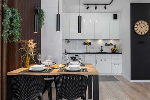 Enjoy meals in the kitchen and dining area with a clean, minimalist design featuring a wooden table and black chairs.