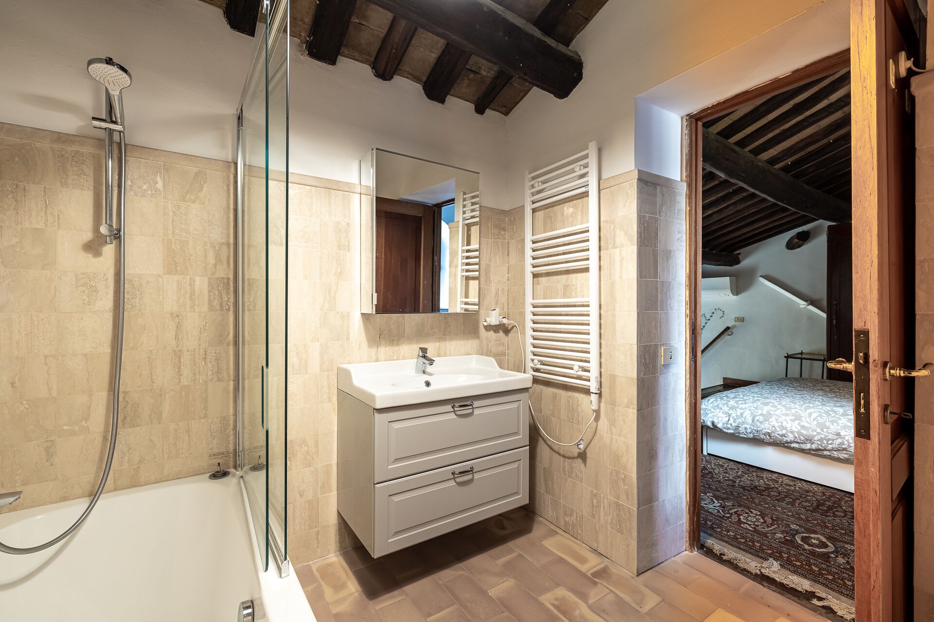 A bathroom with a glass shower enclosure, a white sink, and a mirror.
