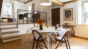 A dining area with a table set for four, a staircase, and a view of the outside. - Castello del Duca (Rome)