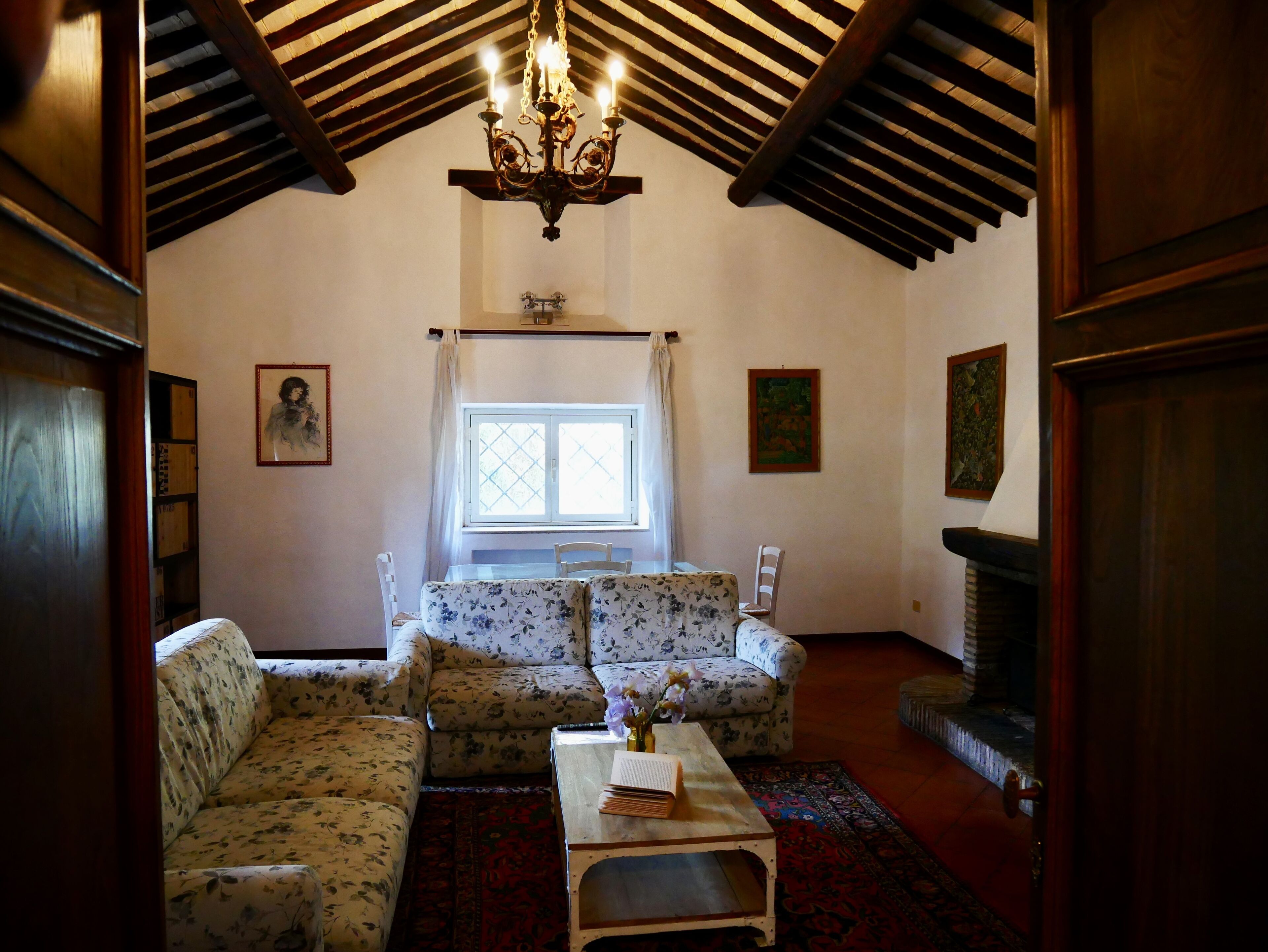 A cozy living room with floral-patterned sofas, a wooden coffee table, a chandelier, and a fireplace.