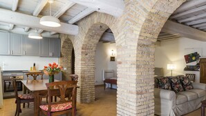 A spacious kitchen with modern appliances, a dining area with a wooden table and chairs, and a living room with a sofa and decorative pillows. - Castello del Duca (Rome)