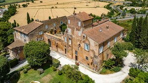 A large, historic building with multiple wings, surrounded by lush greenery and fields. - Castello del Duca (Rome)