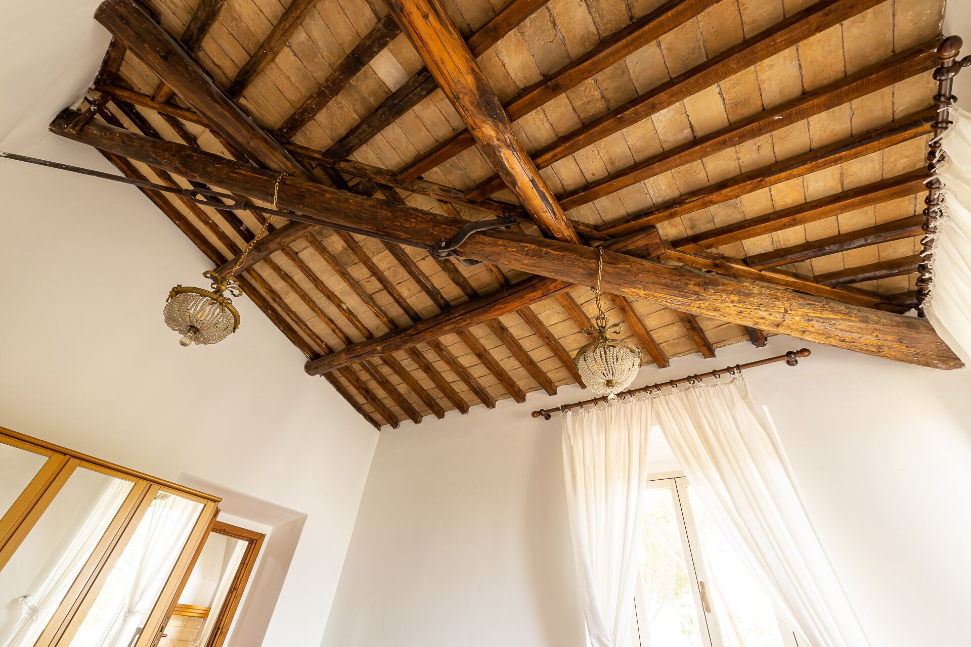 Une pièce avec un plafond en bois, des poutres apparentes et un lustre.