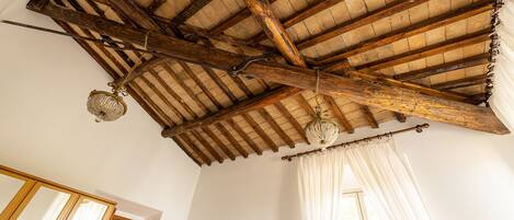 Une pièce avec un plafond en bois, des poutres apparentes et un lustre.