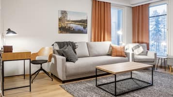 A modern living room with a sofa, a coffee table, a desk, and a lamp.