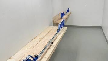 Een kamer met een lange houten bank en een blauwe metalen leuning.