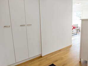 A modern interior with white wardrobes, a wooden floor, and a bright room with a window.