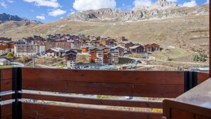 A mountainous town with a mix of modern and traditional buildings, a clear sky, and a wooden bench in the foreground. - Savoy (Lavachet) by Interhome (Tignes)