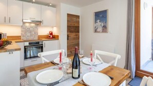 A modern kitchen with white cabinets, a wooden countertop, and a dining area with a wooden table set for two. - Savoy (Lavachet) by Interhome (Tignes)