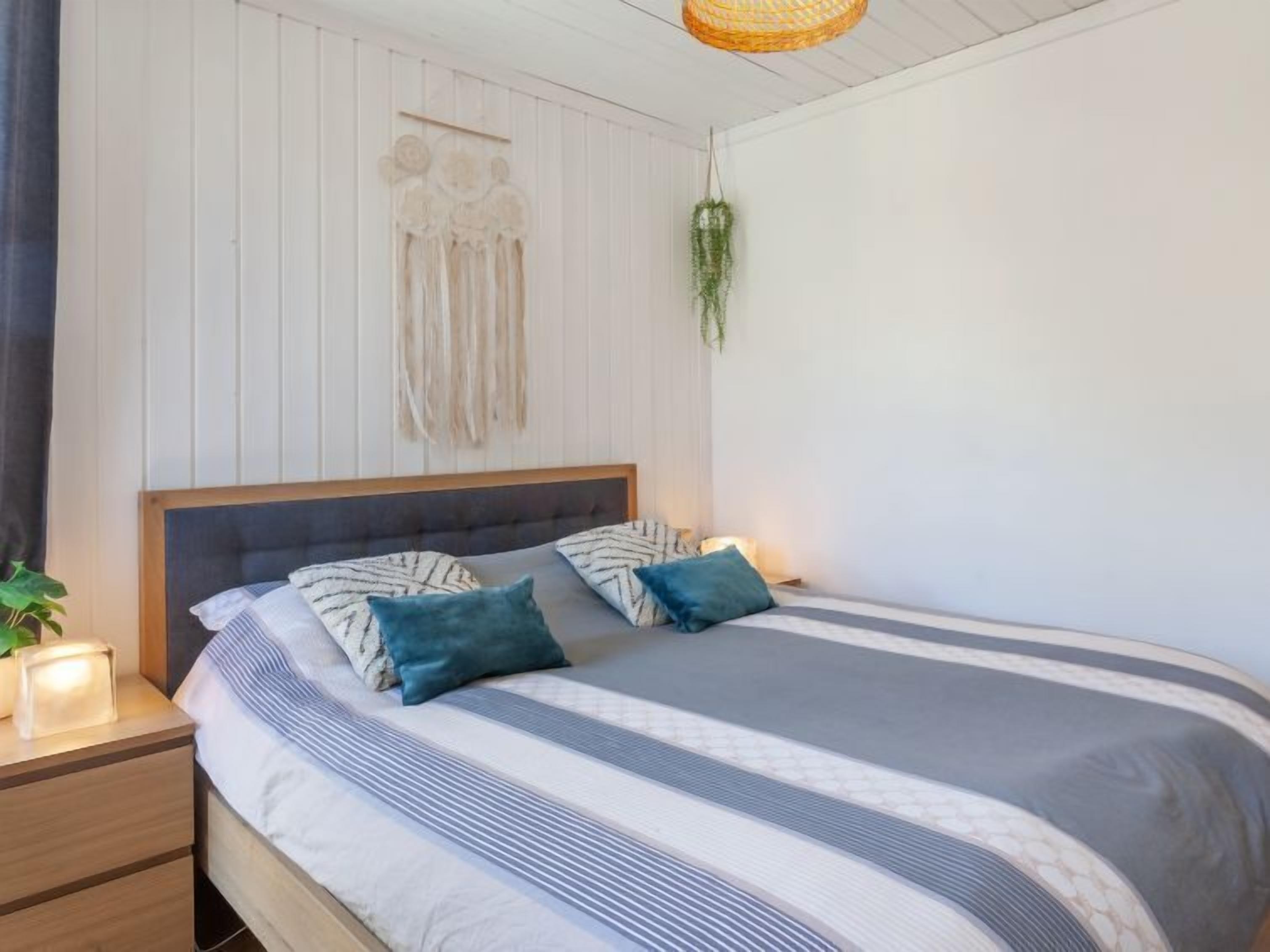 A neatly made bed with striped bedding, a headboard, and decorative pillows.