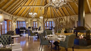 Un espace repas agrémenté de poutres en bois, d’un lustre et d’une cheminée.