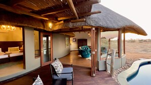 Un espace extérieur avec toit de chaume, une piscine, une terrasse en bois et des sièges.