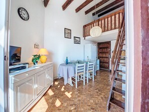 Une cuisine équipée d’une table à manger, de chaises, d’une horloge et d’un escalier menant à un niveau supérieur.