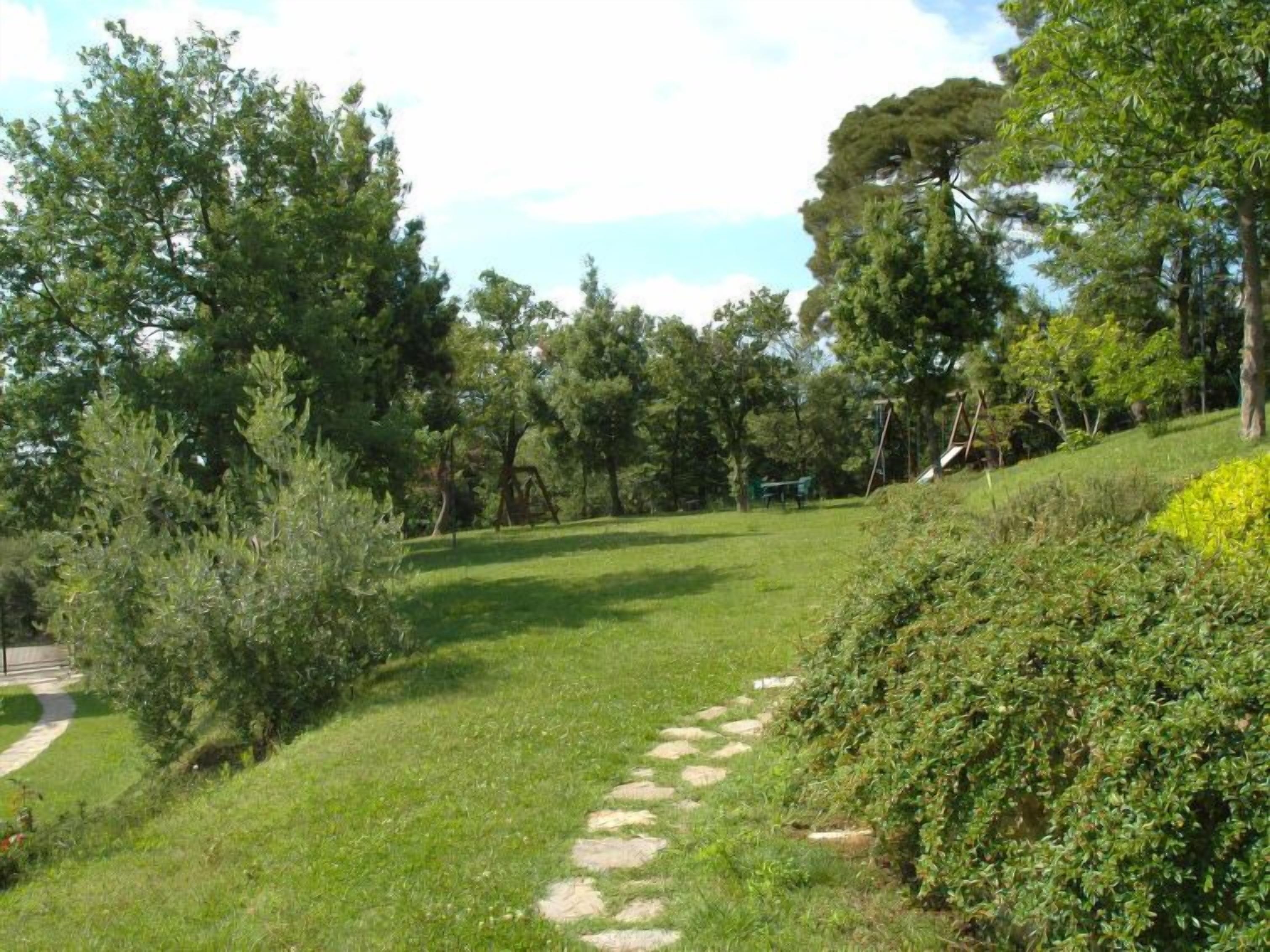 Un sendero de césped con árboles y un columpio en un parque.