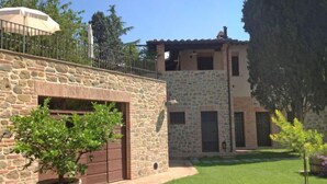 Un edificio in pietra con un garage, un piccolo giardino e una pianta in vaso.